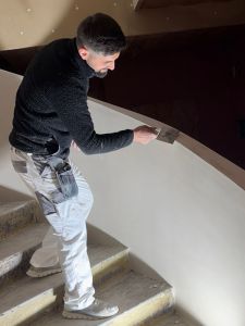 Gipser beim verputzen eine Treppengeländer